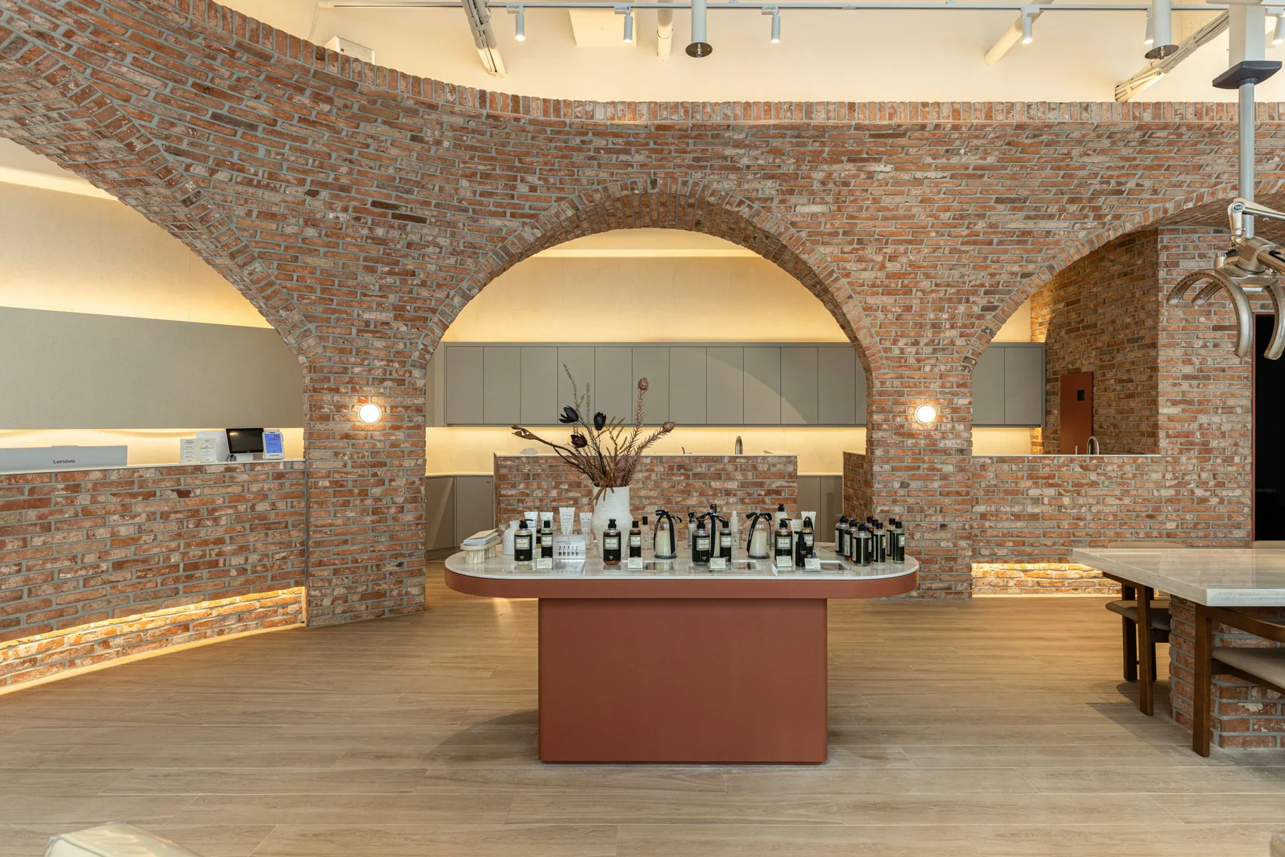 Interior of JUNO HAIR Mangu Station with three red brick arches side by side and a terracotta product display in front