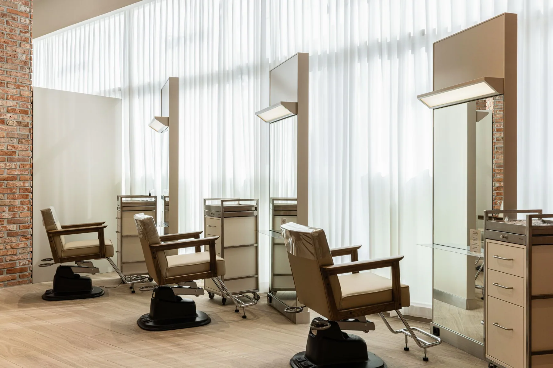 Cream styling chairs and full-length mirrors by the window