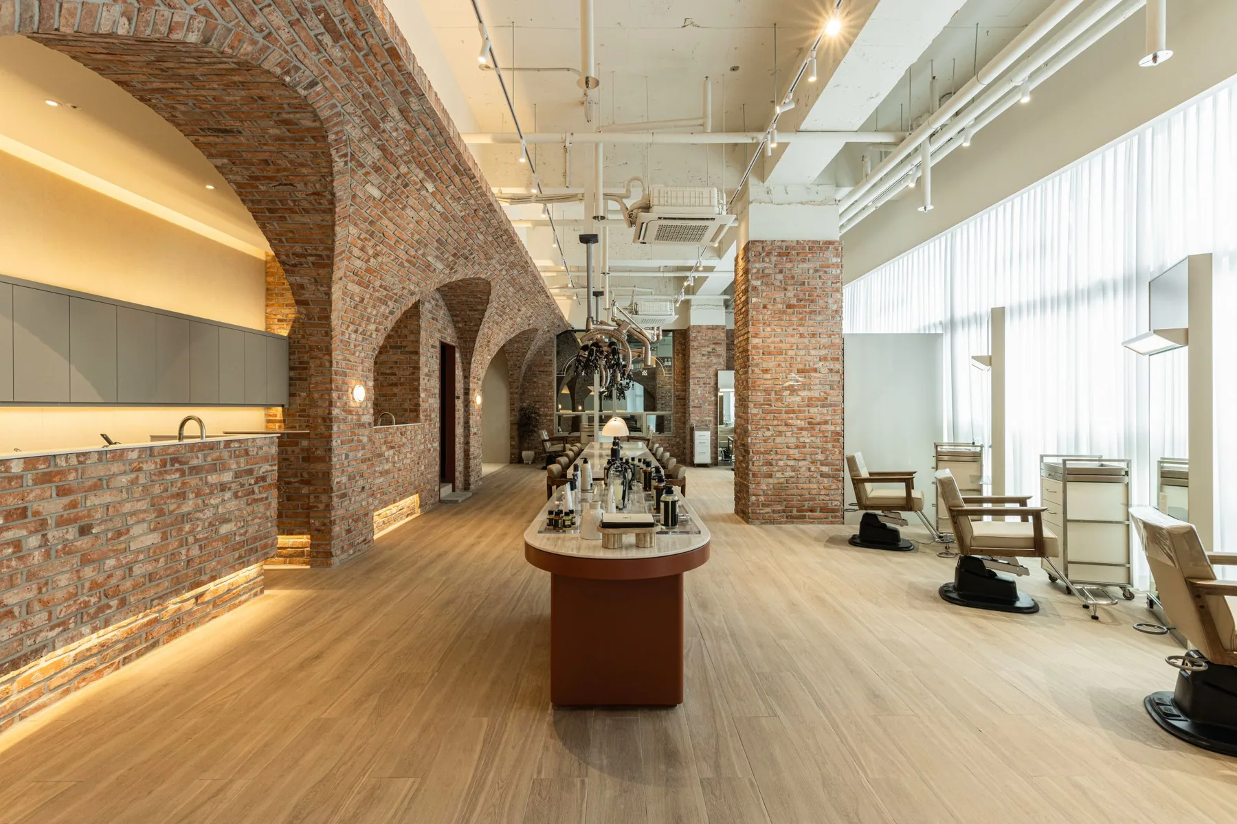 Long view of the JUNO HAIR Mangu Station hall with brick arches running toward the back